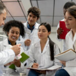 A group of students learning dental treatment from a senior dentist with note and pen in hands at a hospital alike lab.