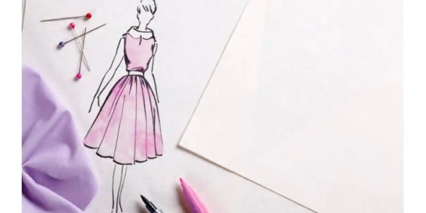 A sketch of a model in a designer dress is drawn on a sheet pf paper; some papers, pins and coloured pens are seen on the table too